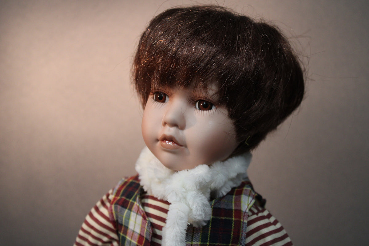 茶髪でチェックのベストを着た男の子の磁器人形のクローズアップ。